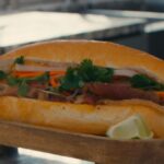 Sliced smoked pork belly banh mi on a Vietnamese baguette with pickled daikon and carrots