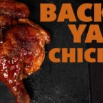 Glazed backyard smoked chicken half sliced on a board